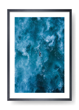 Surfer paddling in the blue sea